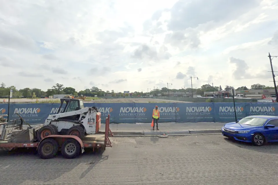 Google Street View of empty construction site with blue construction fence